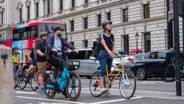 Cyclists waiting at a red light on London Bridge with cars in the background