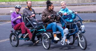 Four people on a non-standard cycle all peddling together on the pavement