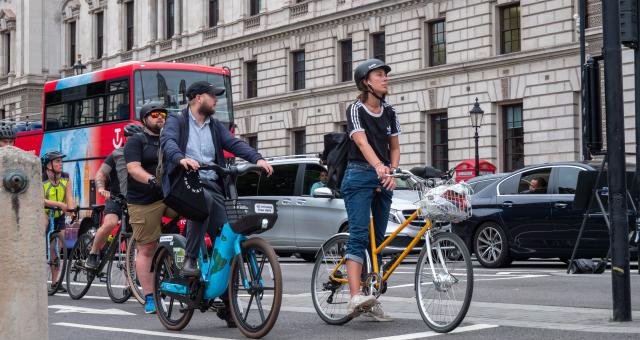 Cyclists waiting at a red light on London Bridge with cars in the background