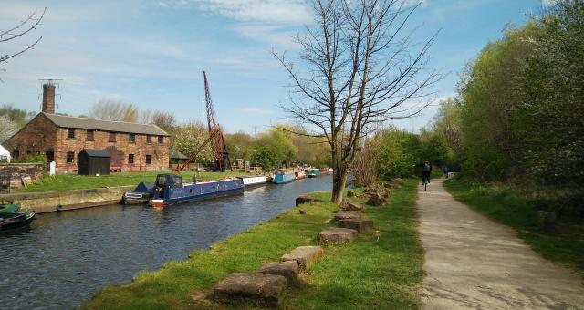 Unicyclists passing Thwaites Mill, alongside the Aire and Calder Navigation