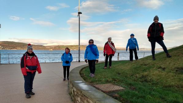 Group of volunteers and staff standing in a row on promenade at seafront