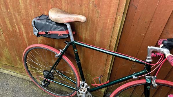The Altura Vortex Waterproof Dropper 7-litre Seatpack fitted to a black road bike with red tyres and red bar tape on its drop handlebar