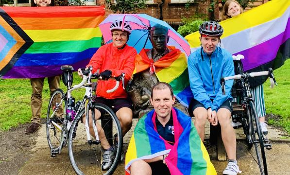 A group of people is posing with rainbow flags and their bikes