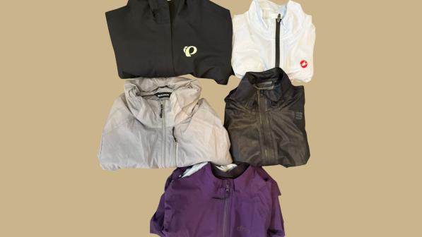 A selection of women's lightweight cycling against a coloured background: a black one with a Pearl Izumi logo, a white one with a Castelli logo, a black one, a purple one and a silver grey one