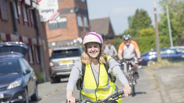 A woman smiling and cycling along through a quiet street