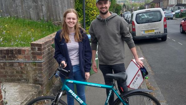 A young man and woman standing in the suburban street with bikes