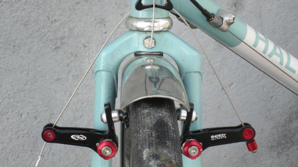 The red and black front cantilever brake in situ on a pale turquoise bike